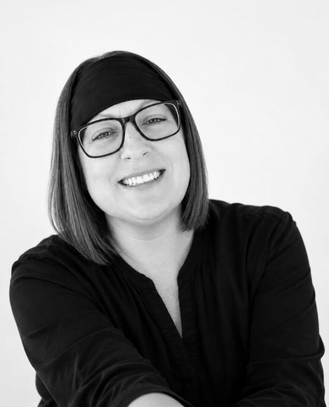 Hillary smiling, wearing glasses and a black headband
